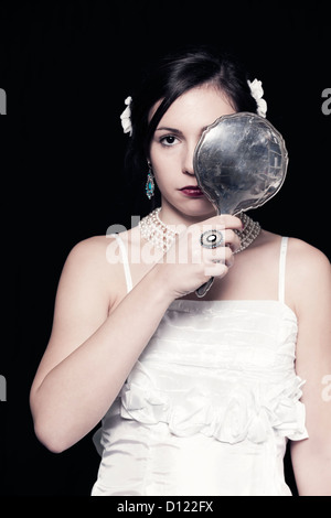 ein Mädchen in einem weißen Kleid mit einem alten handmirror Stockfoto