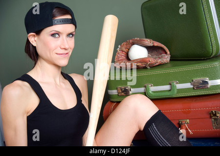 Eine attraktive Frau sitzt vor ihr Gepäck mit ihrem Baseball-Ausrüstung Stockfoto