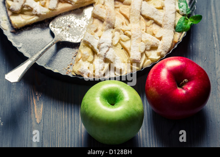 Zwei Äpfel und frisch gebackenem Apfelkuchen auf alte blaue Tabelle Stockfoto