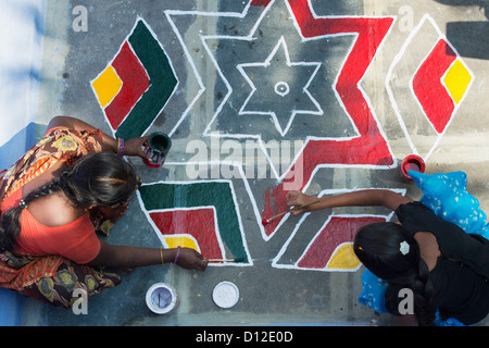 Junge indische Frau und Teenager-Mädchen eine Rangoli Design vor einem ländlichen Haus indische Malerei. Andhra Pradesh, Indien Stockfoto