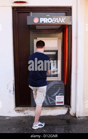 Ein Tourist zieht Bargeld von einem Geldautomaten in der Altstadt von Rethymno, Kreta, Griechenland. Stockfoto