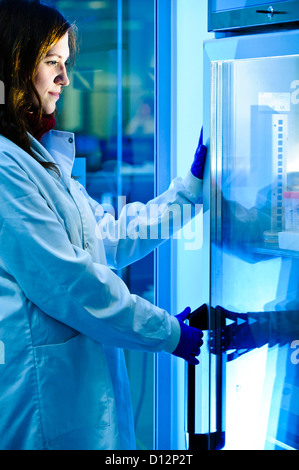 Junge Wissenschaftlerin in Science Lab tatenlos Probe Kühlschrank Stockfoto
