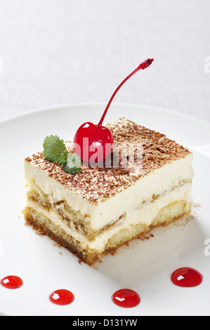 Tiramisu - klassische Dessert mit Kaffee auf weißen Teller. Garniert mit Cherry und Mint. Stockfoto
