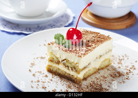 Tiramisu - klassische Dessert mit Kaffee auf weißen Teller. Garniert mit Cherry und Mint. Stockfoto