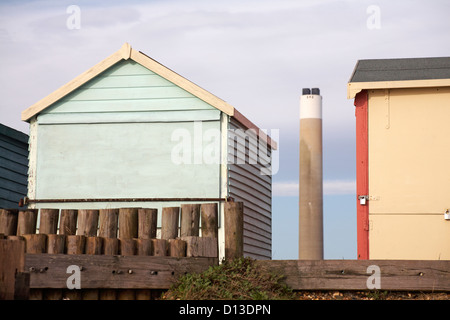 Strand Hütten mit Blick auf Fawley Power Station Tower dazwischen bei Calshot, Hampshire im November Stockfoto