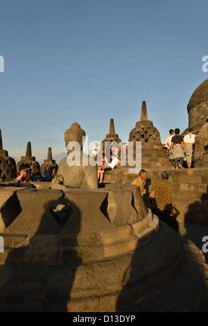 Touristen durchstreifen Sie die ätherischen Buddha an der Spitze des atemberaubenden Borobudur; Zentraljava, Indonesien. Stockfoto