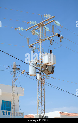 Transformatoren von einem elektrischen Post mit Powerlines gegen strahlend blauen Himmel Stockfoto