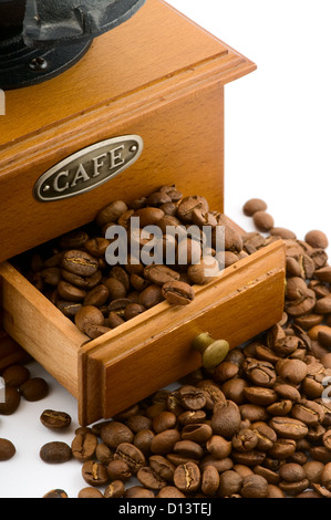 hölzerne Kaffeemühle mit Bohnen auf weiß Stockfoto