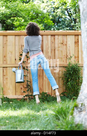 junge Frau im Garten versuchen, über den Zaun zu schauen Stockfoto