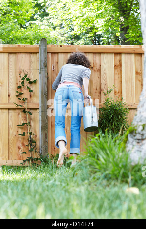 junge Frau im Garten versuchen, durch den Zaun zu schauen Stockfoto