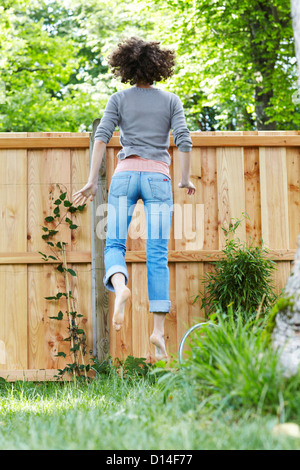 junge Frau im Garten versuchen, über den Zaun zu schauen Stockfoto