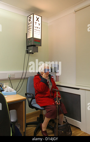 Eine alte Frau mit ihrem getestet Augen für Katarakt eine Sehtafel Test lesen Stockfoto