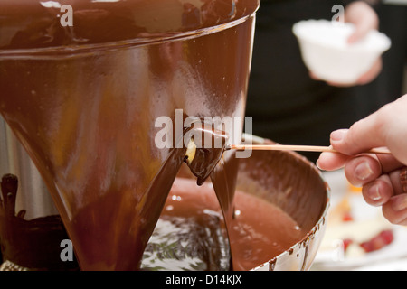 Scheibe Ananas, die gerade frisch in warmer Milch Schokolade Fondue getaucht wurden. Stockfoto