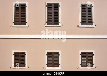 Detail der Fassade des Hauses mit geschlossenen Fenstern mit hölzernen Jalousien Stockfoto