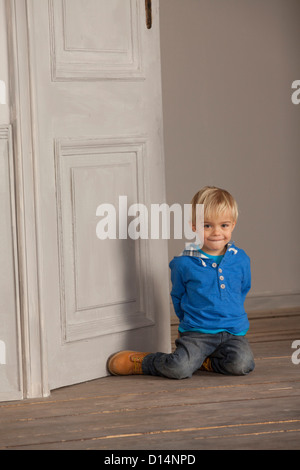 Junge sitzt auf Holzboden Stockfoto