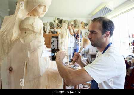 Bildhauer Meißeln Figur aus Holz Stockfoto