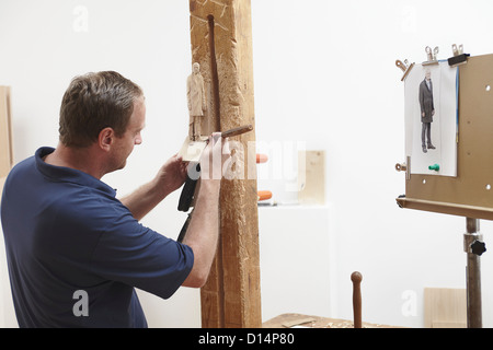 Arbeiter Meißeln Figur aus Holz Stockfoto