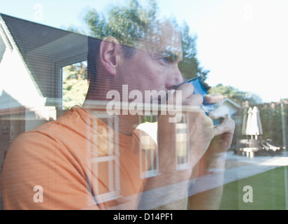 Mann mit Kaffee spiegelt sich im Fenster Stockfoto