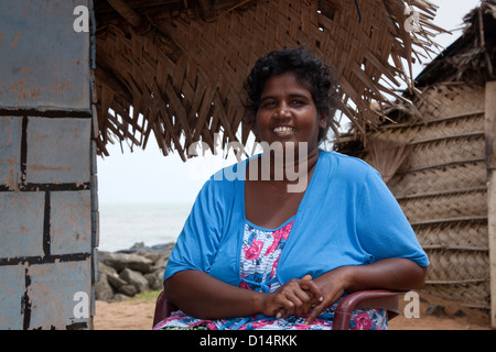 Frau aus dem Dorf Waikkal, Sri Lanka, sitzt auf einem Kunststoff Sitz vor ihrem Haus Stockfoto