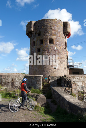 Frau Radfahrer am Archirondel Turm, le Havre de Fer, Ostküste Jersey, Kanalinseln, Großbritannien Stockfoto