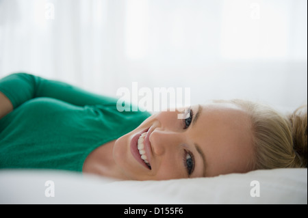 USA, New Jersey, Jersey City, Porträt der lächelnde junge Frau im Bett liegend Stockfoto
