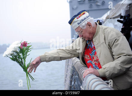 Peral Harbor, Hawaii, USA. 7. Dezember 2012. Pensionierter Marine Seemann First Class Duane Reyelts, ein Überlebender des japanischen Angriffs auf Pearl Harbor, wirft Blumen von der Seite der geführte Raketen Fregatte USS De Wert während einer Zeremonie, Pearl Harbor Tag 7. Dezember 2012. Die Zeremonie begingen den Jahrestag der 7. Dezember 1941 Überraschung japanischen Angriff auf Pearl Harbor. Stockfoto