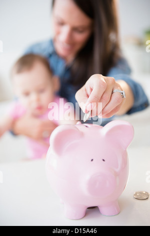 USA, New Jersey, Jersey City, Mutter mit Tochter (6-11 Monate) Sparschwein Münzen Inbetriebnahme Stockfoto