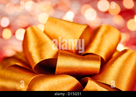Goldenes Band Geschenk Bogen Closeup mit festlichen Lichtern Stockfoto