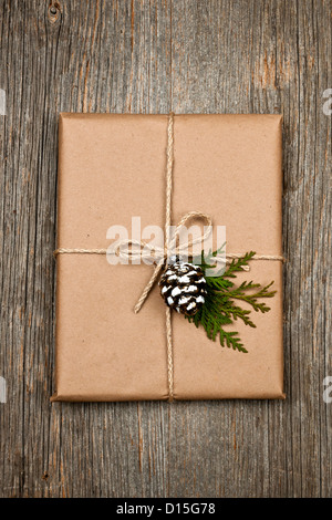 Weihnachts-Geschenk in braunen Verpackung und String mit Kiefer Kegel Dekoration am alten Holz Hintergrund Stockfoto