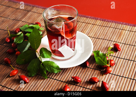 Tasse Tee und reif hip Rosen (Heckenrose Frucht) auf hölzernen Hintergrund Stockfoto