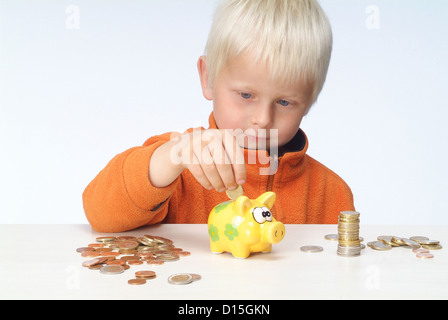 Hamburg, Deutschland, füllt ein Junge sein Sparschwein Stockfoto