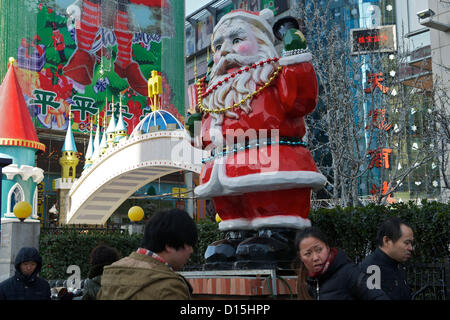 Chinesische Fußgänger Vorbeigehen einen riesigen Weihnachtsmann außerhalb eine Warenbörse am 8. Dezember 2012 in Peking, China. Stockfoto