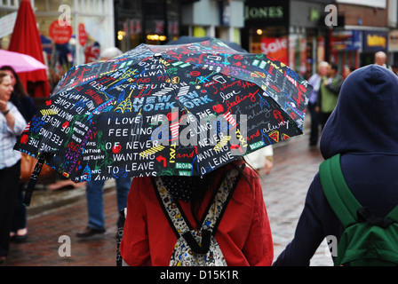 Zuflucht vor dem Regen mit bunten Regenschirm (Canterbury UK) Stockfoto