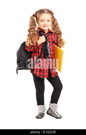 In voller Länge Portrait eines kleinen Mädchens stehend mit Rucksack und Buch isoliert auf weißem Hintergrund Stockfoto