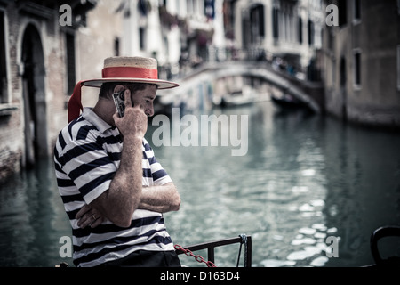 Gondoliere sprechen am Telefon durch einen Kanal in Venedig Stockfoto