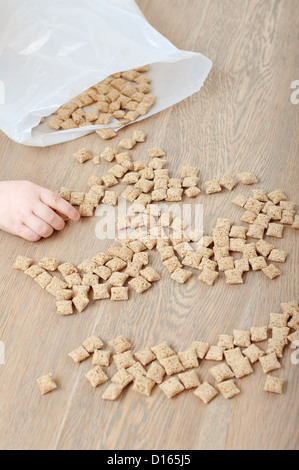 Ein Kind "arm hob die knusprigen Flocken in Form einer smily Fläche verstreut auf dem Holztisch Stockfoto