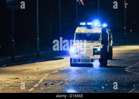 Zwei gepanzerte PSNI Landrover fahren entlang einer Straße mit Geschwindigkeit in der Nacht, mit Blaulicht blinkt Stockfoto