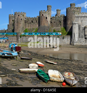 Bahnlinie & historischer Conwy Castle Arriva Zug verlässt Robert Stephenson Eisenbahnbrücke über River Conwy kleine Boote auf Vorschiff Clwyd North Wales UK Stockfoto