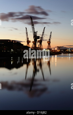 Sonnenuntergang über die Krane bei BAE Systems Werft neben dem Fluss Clyde in Govan, Glasgow, Schottland, Großbritannien Stockfoto