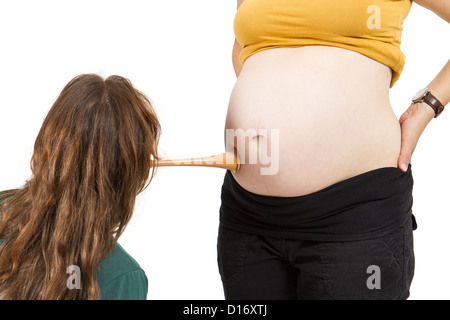 junge Hebamme am menschlichen Bauch hören. Schwangere Frau stehen, während vorne, Hebamme sitzt Stockfoto