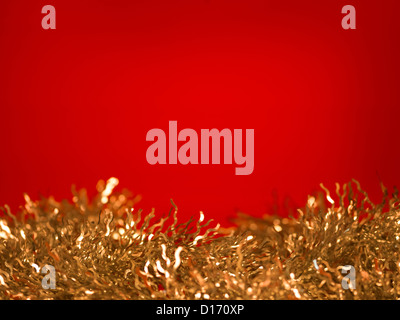 Nahaufnahme des goldenen Lametta auf rotem Grund, untere Grenze Stockfoto