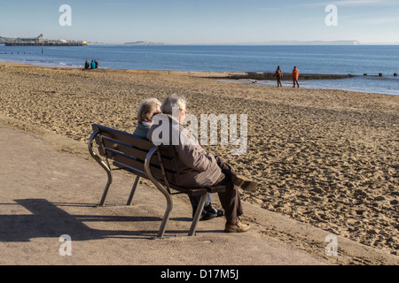 Bournemouth, ältere Paare, Sitzen, auf das Meer, die Promenade und den Strand, die Bucht von Poole, Dorset, England, UK. Europa Stockfoto