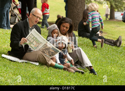 Mixed-Rennen Familie entspannt auf grasbewachsenen Hügel als weißer Mann Zeitung-Programm für die Texas Book Festival in Austin, Texas liest Stockfoto