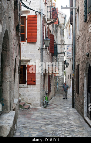 Mann zu Fuß durch die engen, gepflasterten Gassen der Altstadt von Kotor in Montenegro. Stockfoto