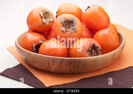 Frische exotische tropische Reife saftige orange Früchte Persimone Diospyros in Holzplatte am Tisch serviert Stockfoto