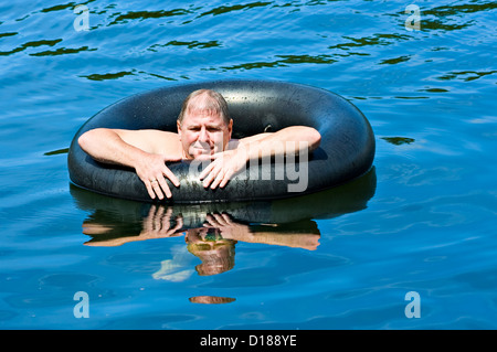 Ein Mann im Wasser schwimmend auf einem Innenrohr Stockfoto