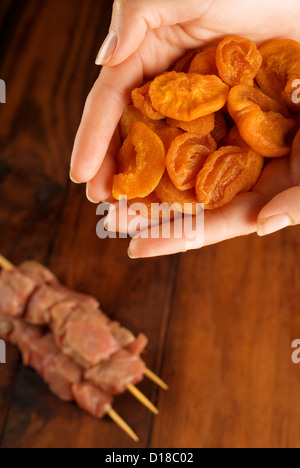 Chefs hands preparing beef skewer kebabs with apricots fruit Stockfoto