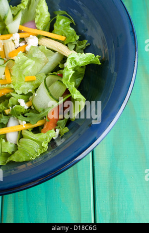 Grüner Salat in blau Schüssel auf Holztisch Stockfoto