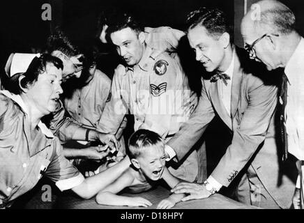 Mehrere Ärzte und Krankenschwestern zurückhalten junge Ernest Booth. Stand war einer der 30.000 Kinder erhalten Gamma-Globulin-Impfungen Stockfoto