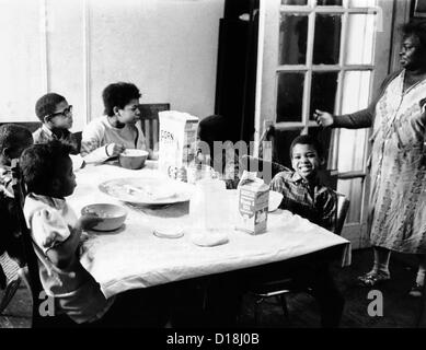 Eine afrikanische amerikanische Mutter dient sechs Kinder ein Frühstück mit Cornflakes und Milch in ihrer Wohnung in New York Harlem Stockfoto